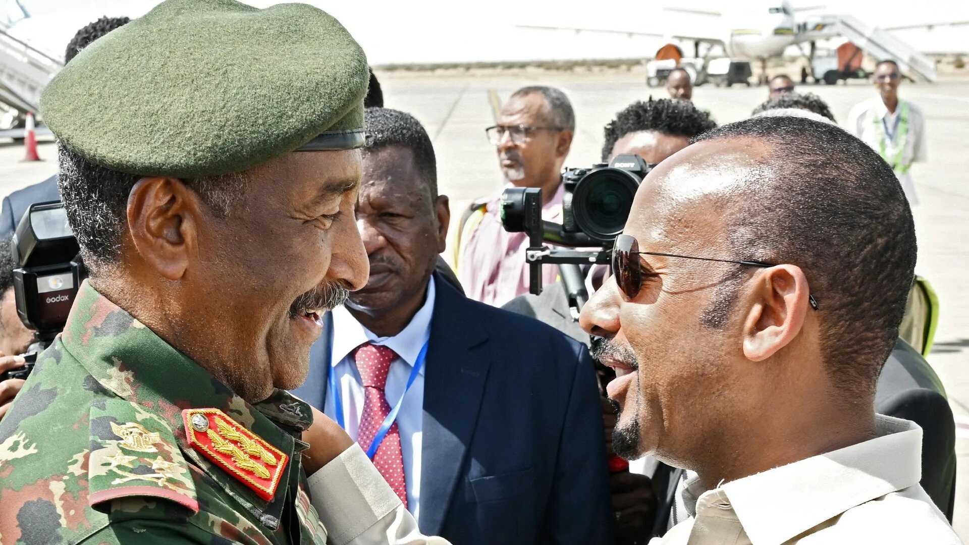 General Abdel Fattah al-Burhan (L) welcomes Ethiopia's Prime Minister Abiy Ahmed, as he arrives for an official visit at Port Sudan International Airport on 9 July (AFP)