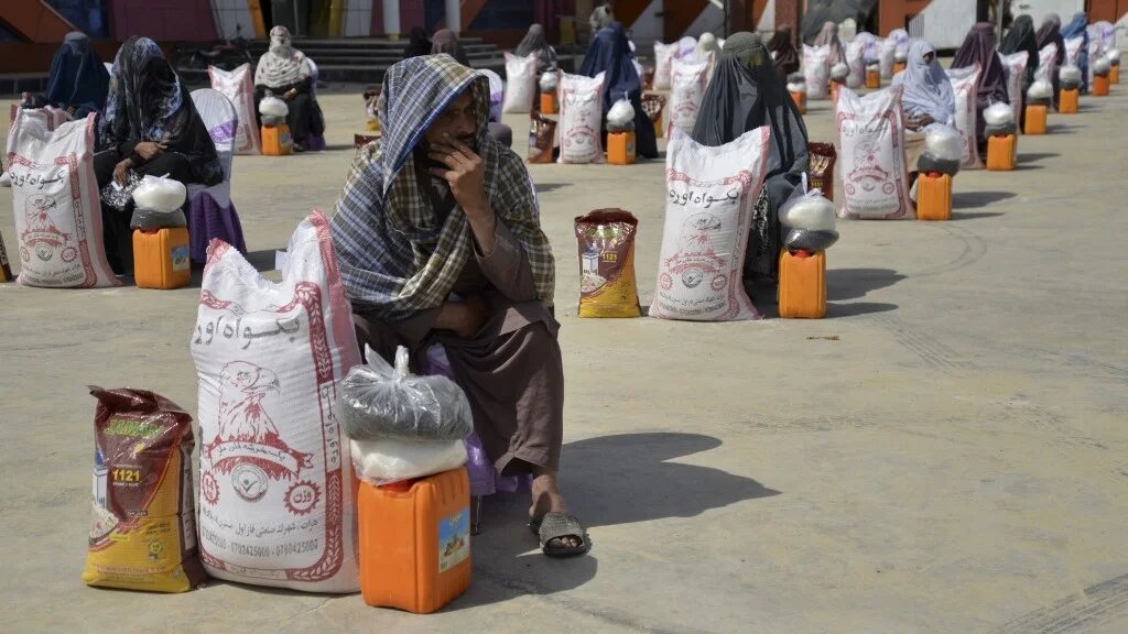 Afghan women sit next to food aid distributed by a charity foundation during the Muslim holy fasting month of Ramadan in Kandahar on March 28, 2023 (AFP)