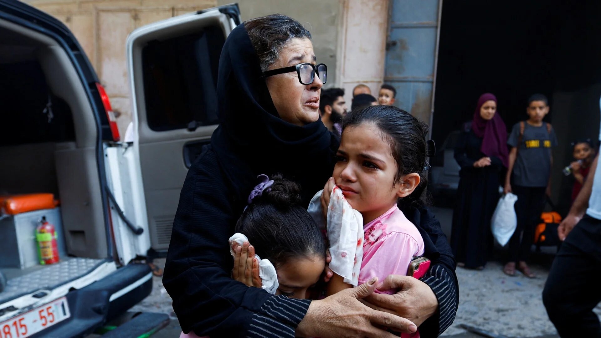 A Palestinian woman and children in the aftermath of Israeli air strikes, in Khan Younis in the southern Gaza Strip, 14 October 2023 (Reuters)
