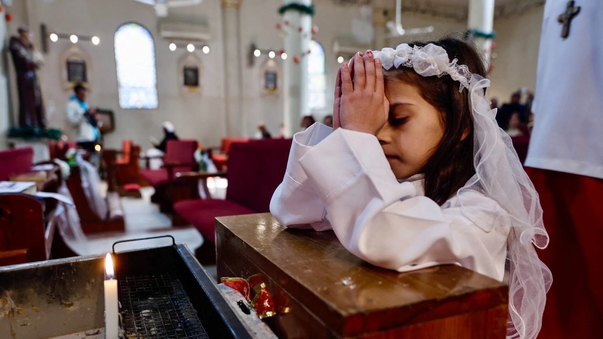 A young Christian girl prays during Christmas celebrations at the Holy Family Church in Gaza City on 21 December 2025 (Omar Al-Qattaa/AFP)