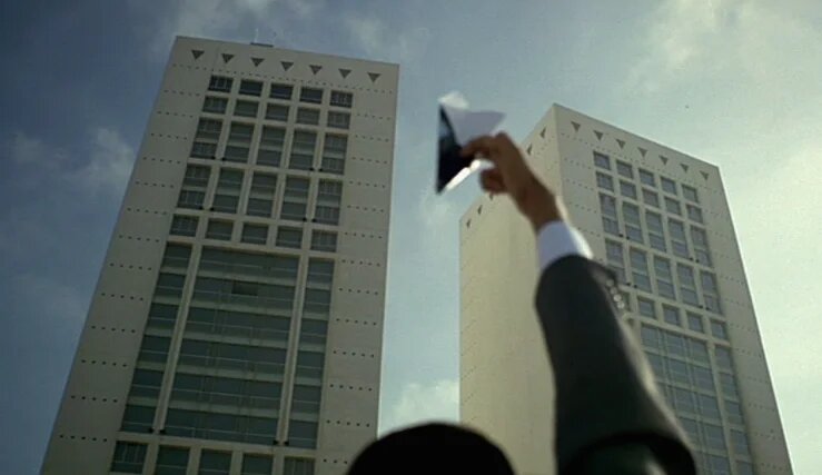 Dans WWW – What a Wonderful World, un plan montre un avion en papier, tenu par la main de Kamel, en train de se diriger vers les tours jumelles du Twin Center de Casablanca, vues en contre-plongée (Gloria Films/Agora Films/Heimatfilm/2M/ZDF/2006)