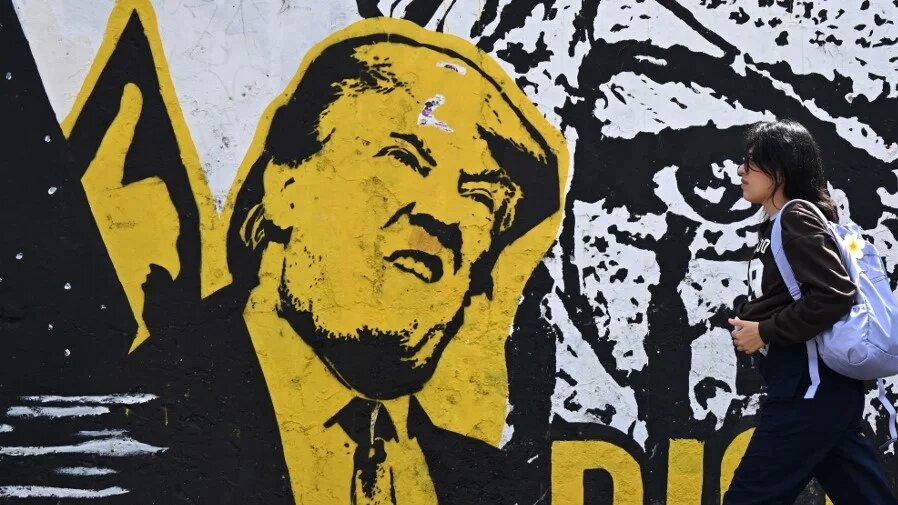 A woman walks past graffiti depicting US President Donald Trump in Bogota, the capital of Colombia, on 18 January 2026 (Raul Arboleda/AFP)