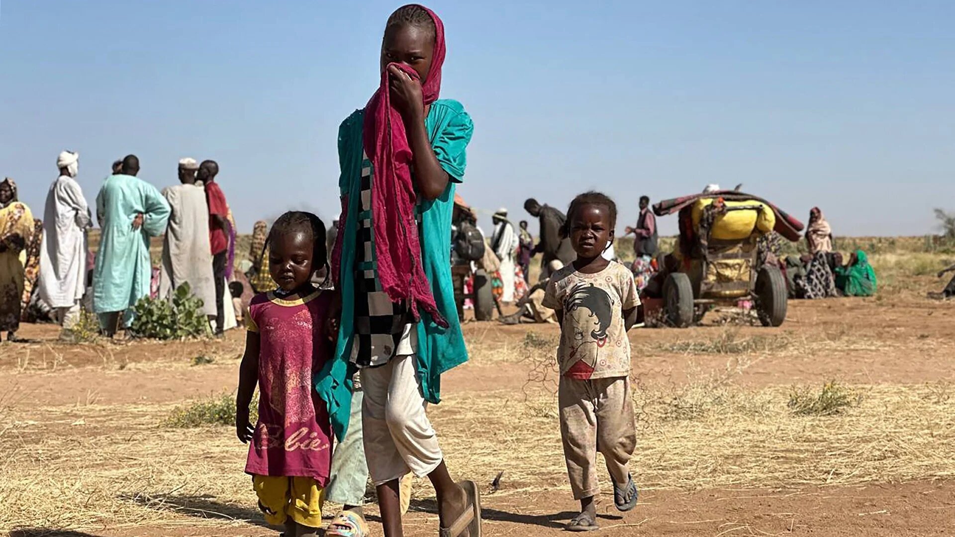 A displaced Sudanese woman, accompanied by children, walks at a camp near the town of Tawila in North Darfur on 11 February 2025 (AFP)
