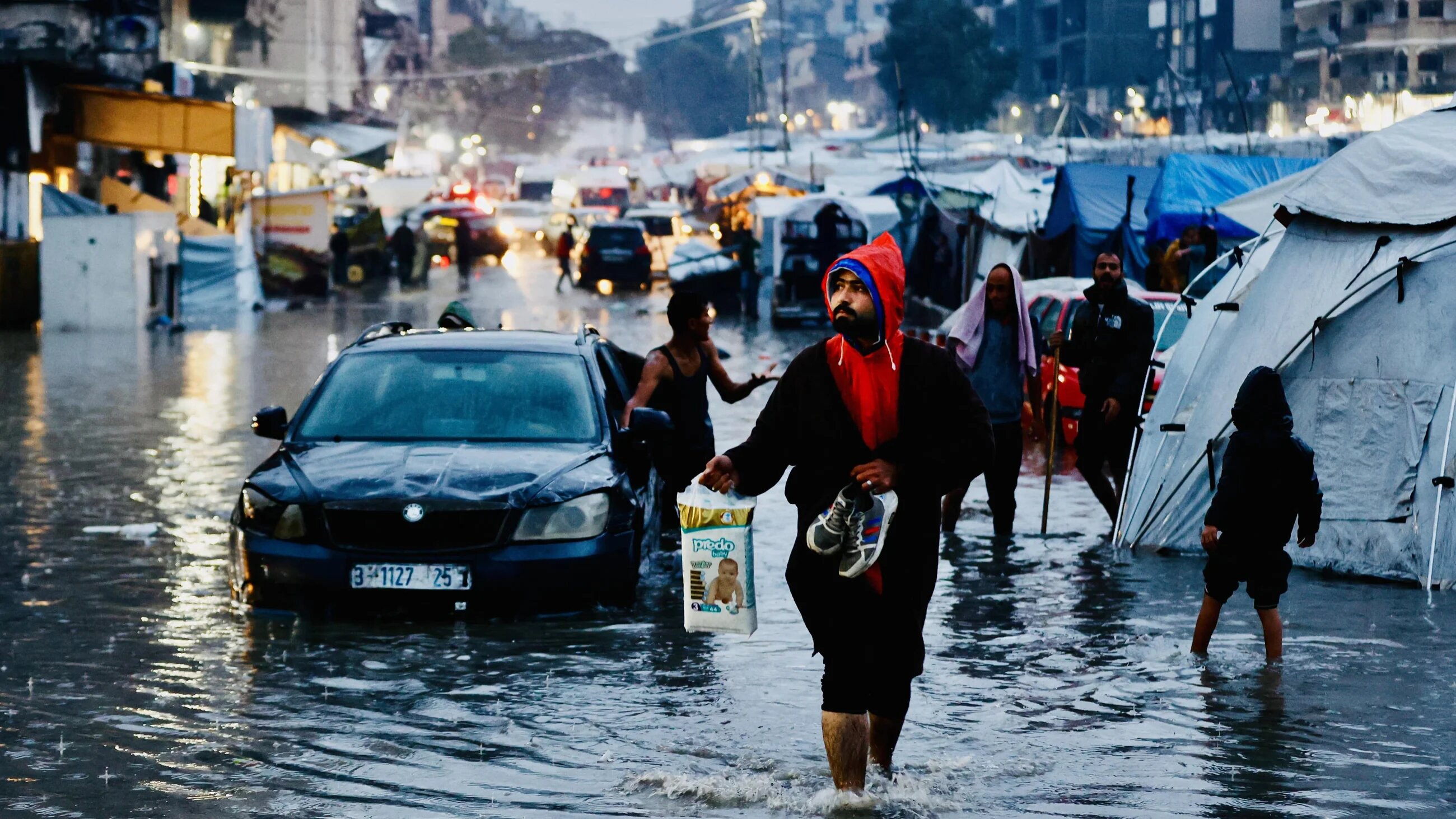 Displaced Palestinians walk through flooded streets following heavy rains in Gaza City on 15 December, 2025 (AFP/Omar al-Qattaa)