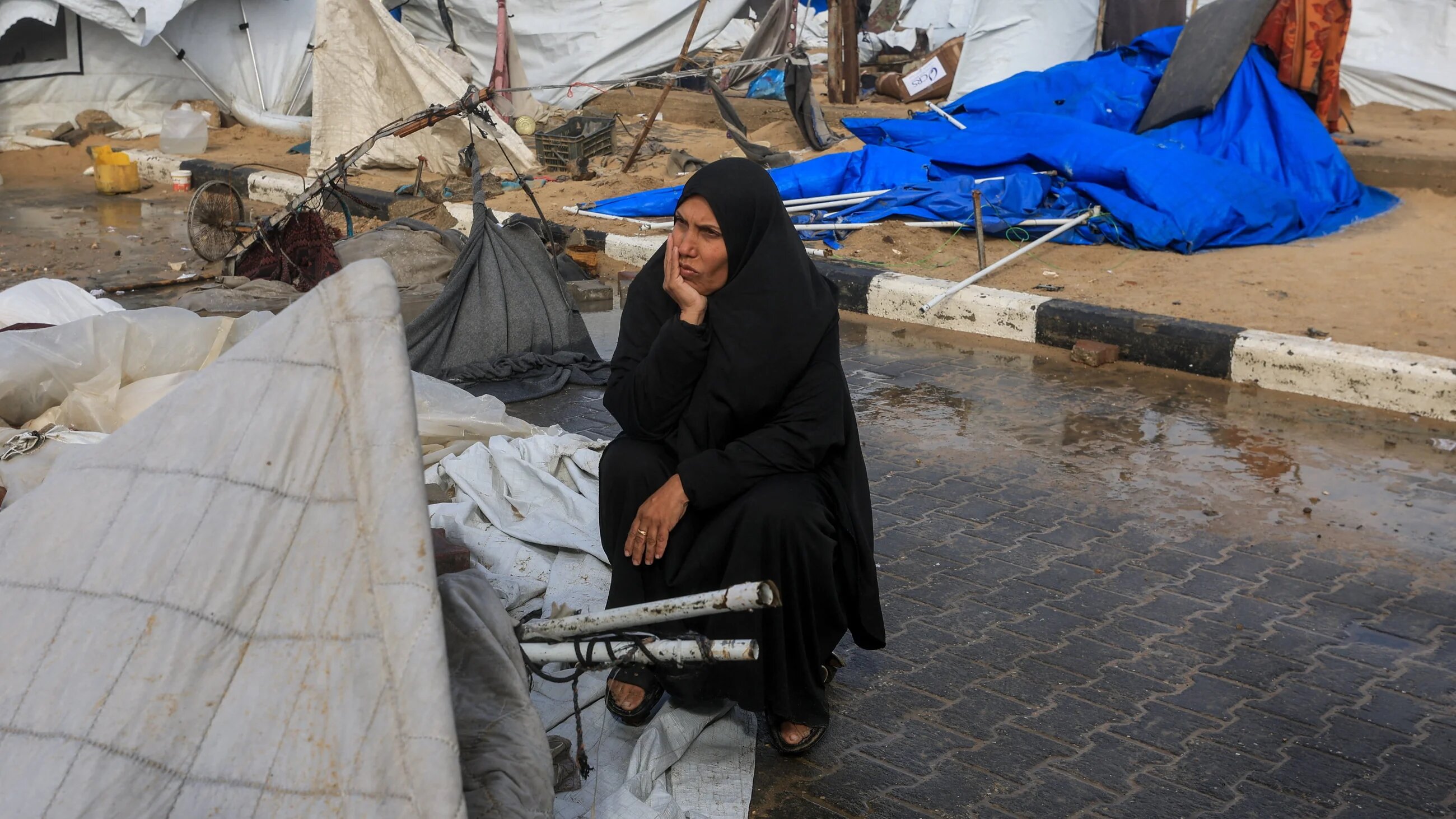 A displaced Palestinian woman sits near damaged tents, amid violent storms in Gaza City, 13 January, 2026 (ReutersDawoud Abu Alkas)