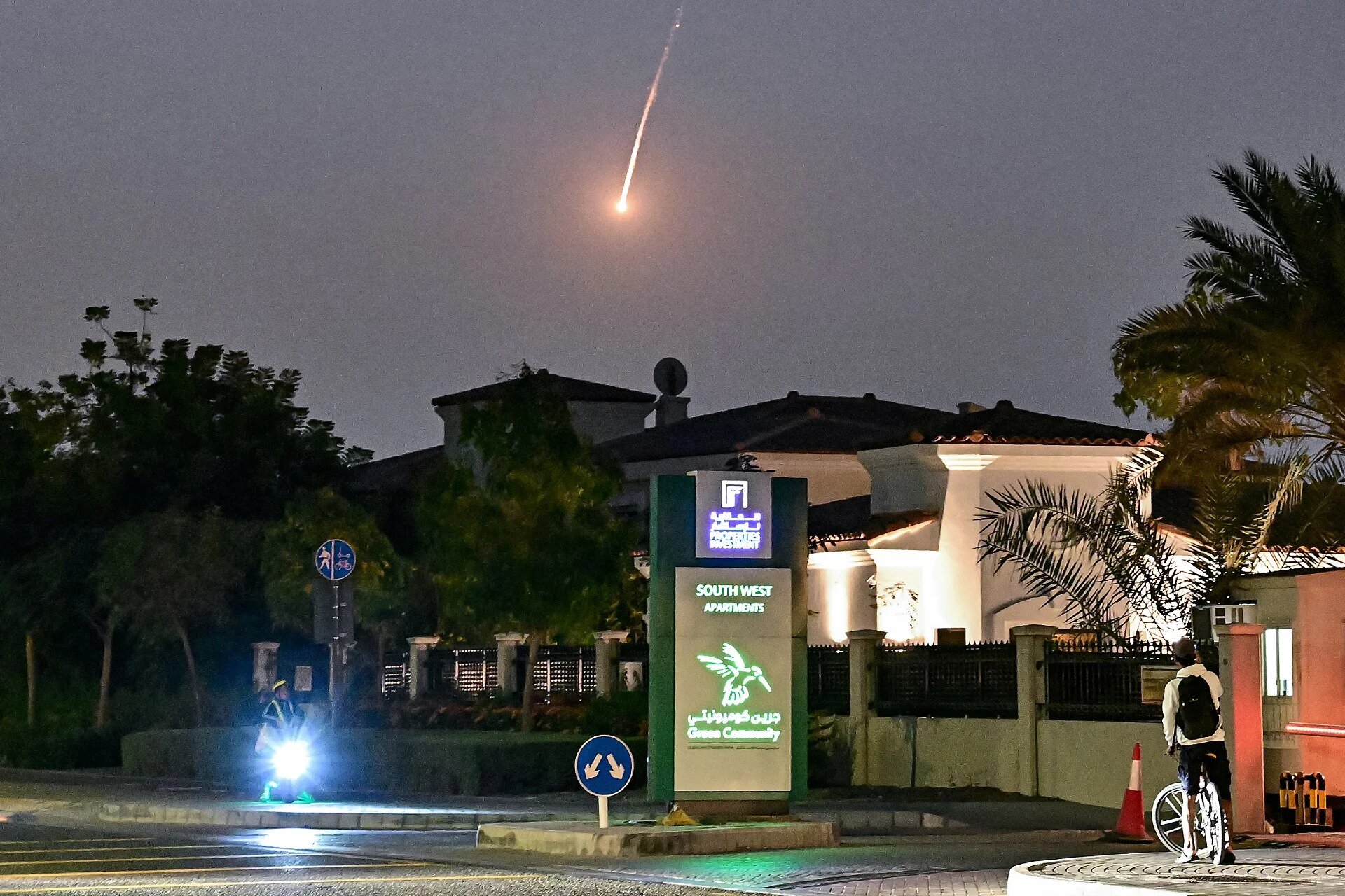 A cyclist watches as a projectile falls over Dubai on 28 February 28, 2026 (AFP)