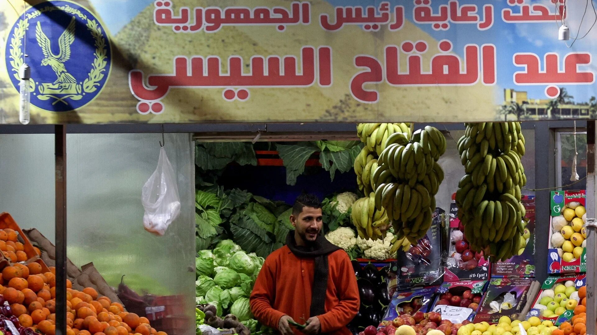A man stands under a banner that reads: 'We are all one, Under the auspices of Egypt's President Abdel Fattah al-Sisi, in a popular market in Cairo, 1 February 2024 (Reuters)