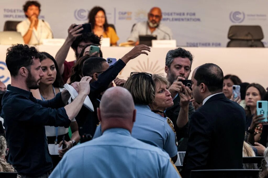 Attendees argue with Egyptian MP Amr Darwish as he interrupts a press conference attended by Sanaa Seif, sister of Alaa Abdel Fattah, on the sidelines of Cop27, 8 November 2022 (AFP)