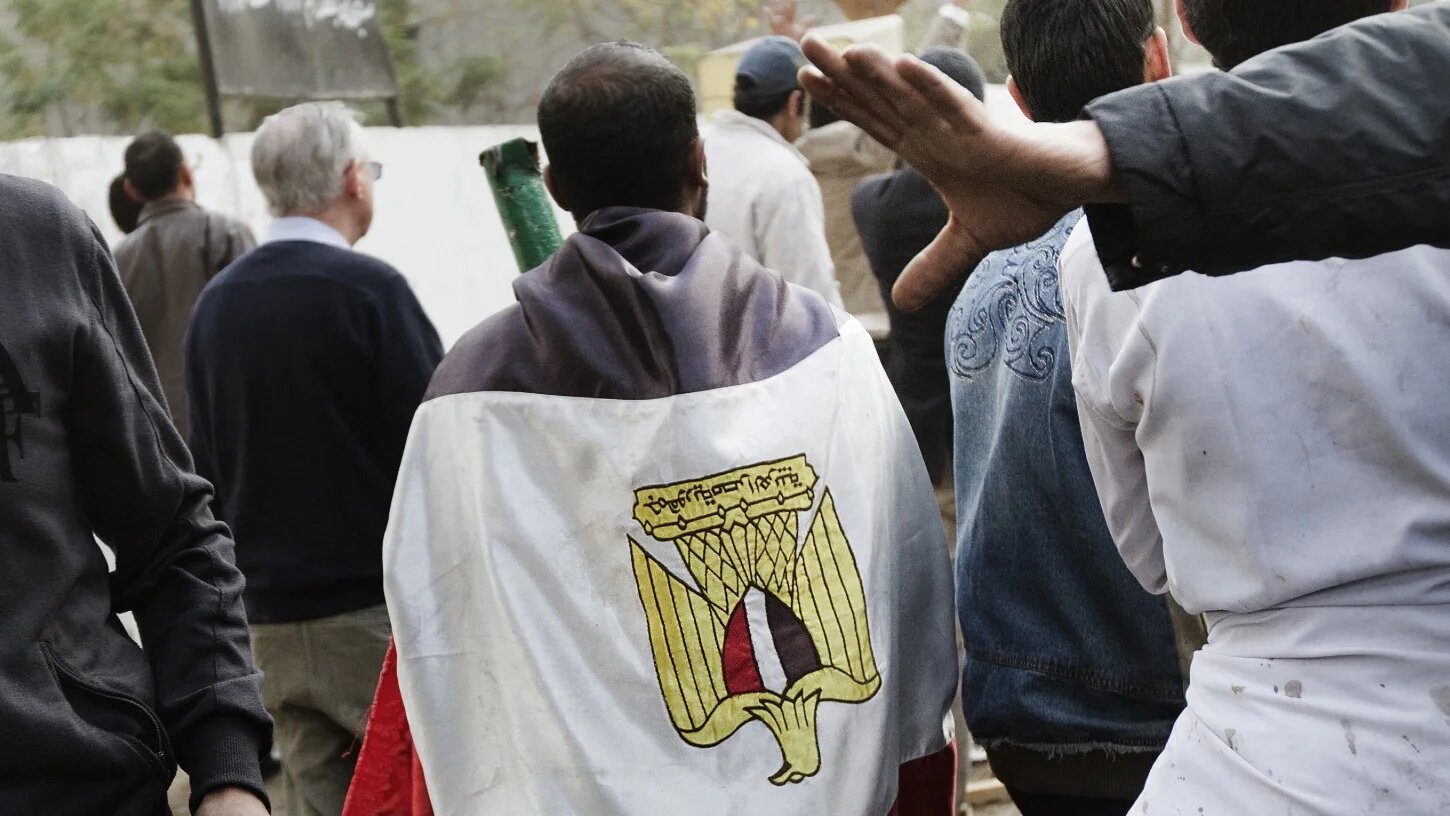 An Egyptian demonstrator wrapped in his national flag joins a protest in central Cairo on 29 January 2011 (Marco Longari/AFP)