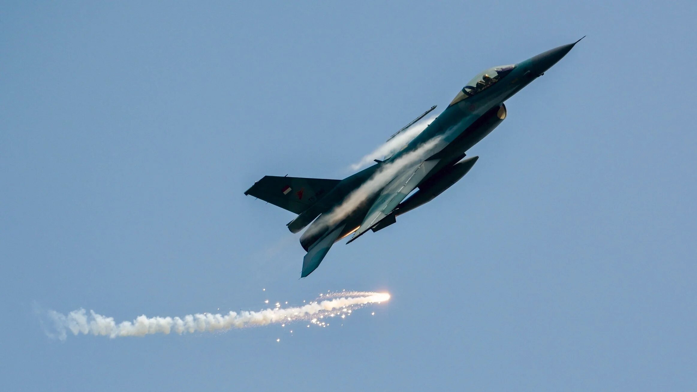 A US-made F16 fighter jet flies past while emitting flares during a rehearsal for the 78th anniversary of the Indonesian military in Jakarta on 3 October 2023 (Bay Ismoyo/AFP)
