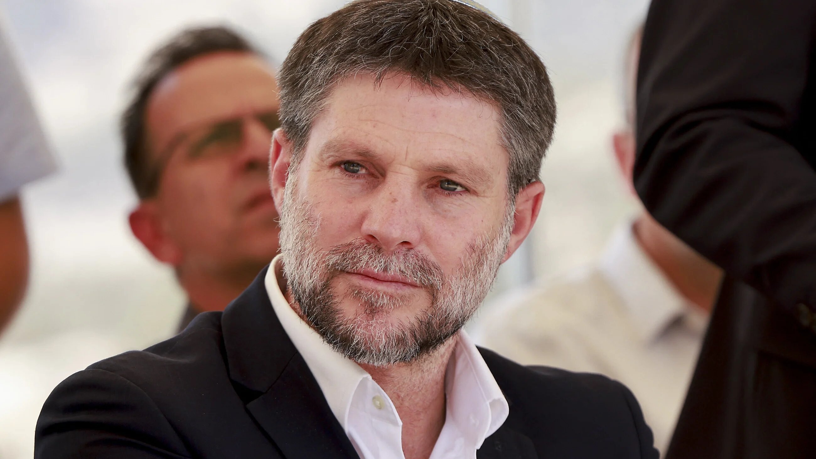 Israeli Finance Minister Bezalel Smotrich sits before a press conference near the settlement of Maale Adumim, in a land corridor known as E1, outside Jerusalem in the occupied West Bank, on 14 August, 2025 (AFP/Menahem)