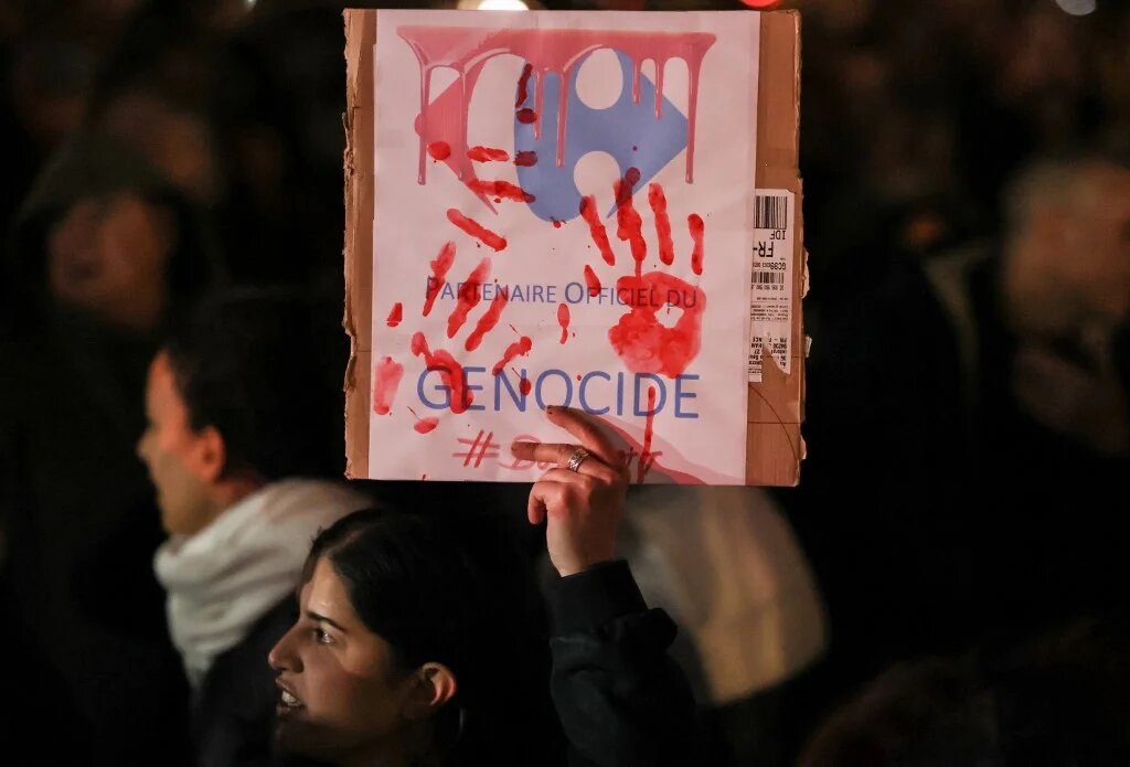 A protester accuses Carrefour of complicity in genocide in Paris, France on 2 November 2023 (Alain Jocard/AFP)
