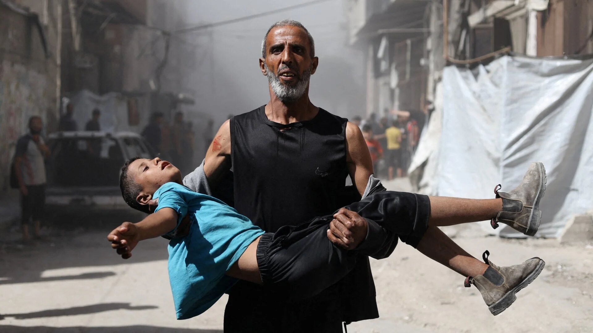 A Palestinian man carries a wounded child after an Israeli air strike on a house, in Gaza City, 7 September 2025 (Reuters/Khamis Al-Rifi)