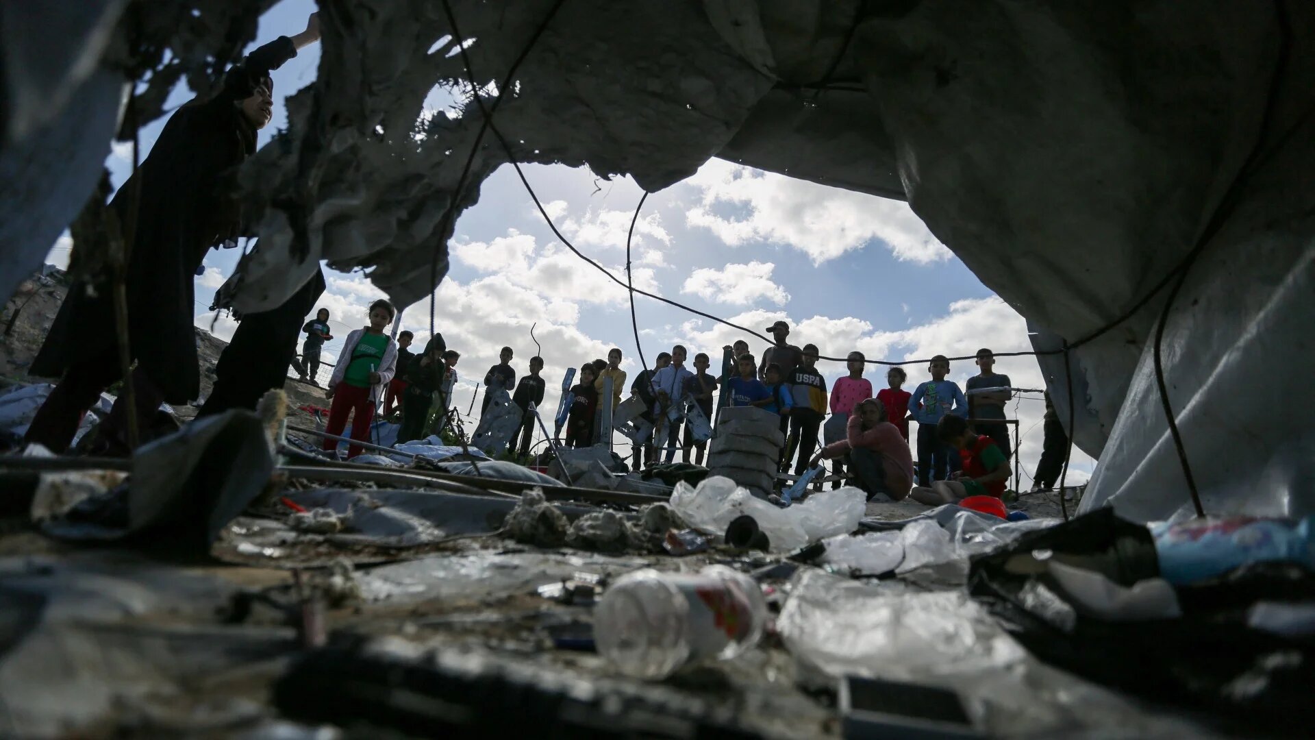 Palestinian children gather at the site of an Israeli strike on a tent housing displaced people, in Khan Younis, in the southern Gaza Strip, 19 March (Reuters/Hatem Khaled)