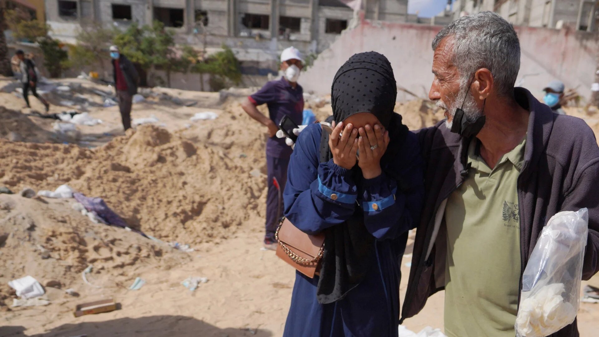Palestinians react after the body of a relative was found buried by Israeli forces in Nasser hospital in Khan Younis on 21 April (AFP)