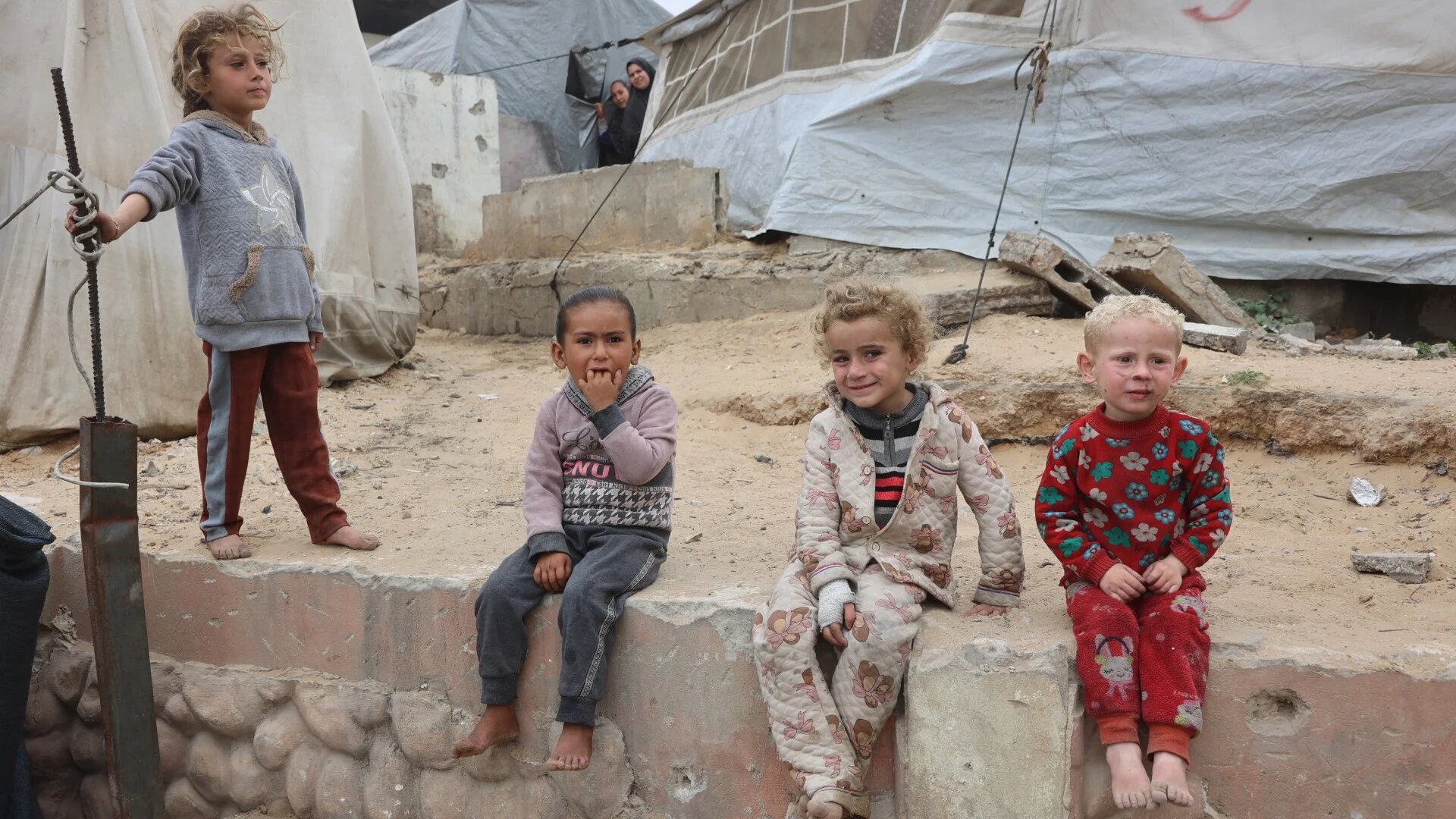 Palestinian children sit by tents at a makeshift displacement camp set up amid building rubble in Gaza City on 12 May 2025 (AFP/Omar al-Qattaa)