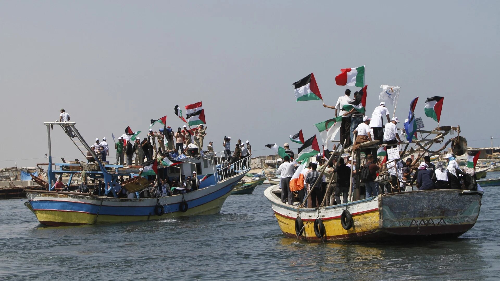 Palestinians waving national flags wait aboard fishing boats at the port of Gaza City on 30 May 2010 to greet the "Freedom Flotilla" carrying tonnes of supplies and a handful of European MPs and hundreds of pro-Palestinian activists (AFP/Mahmud Hams)