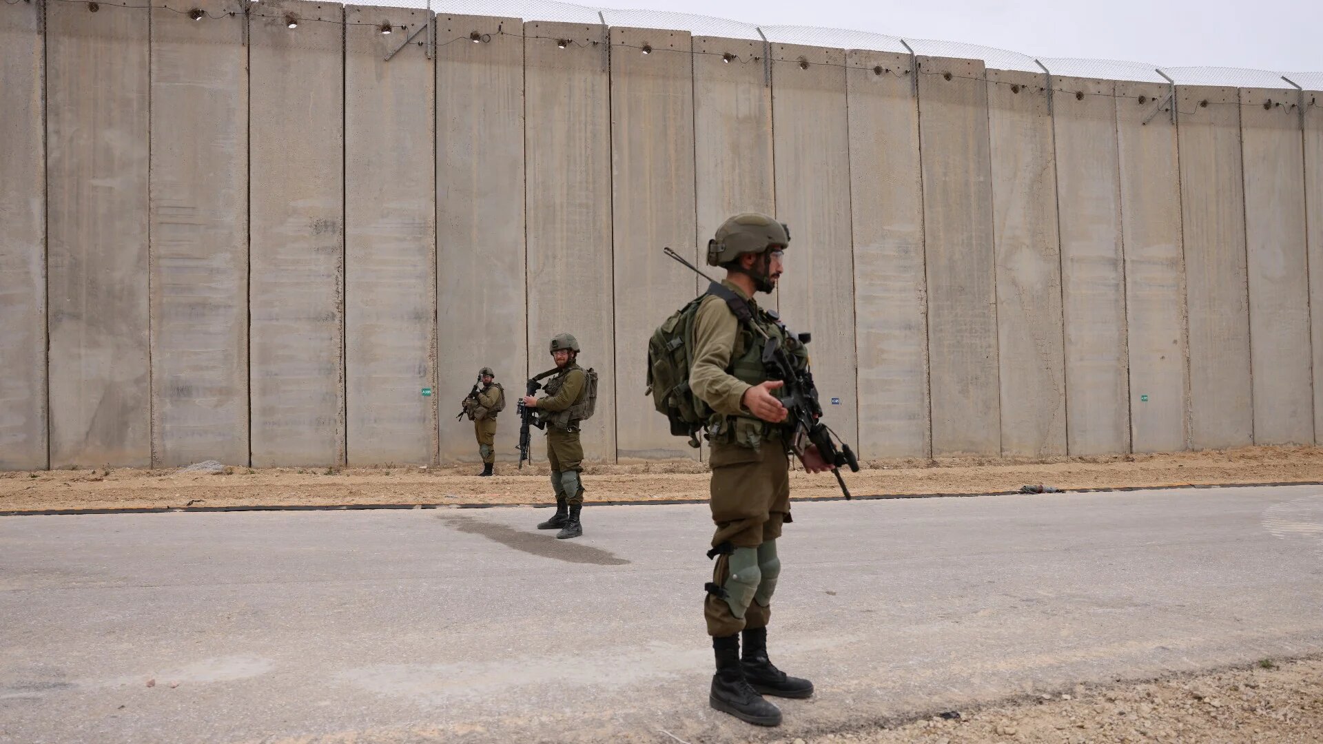 Israeli soldiers stand by the fence along the border with the Gaza Strip near Moshav Netiv HaAsara in southern Israel on 7 December 2021 (AFP)