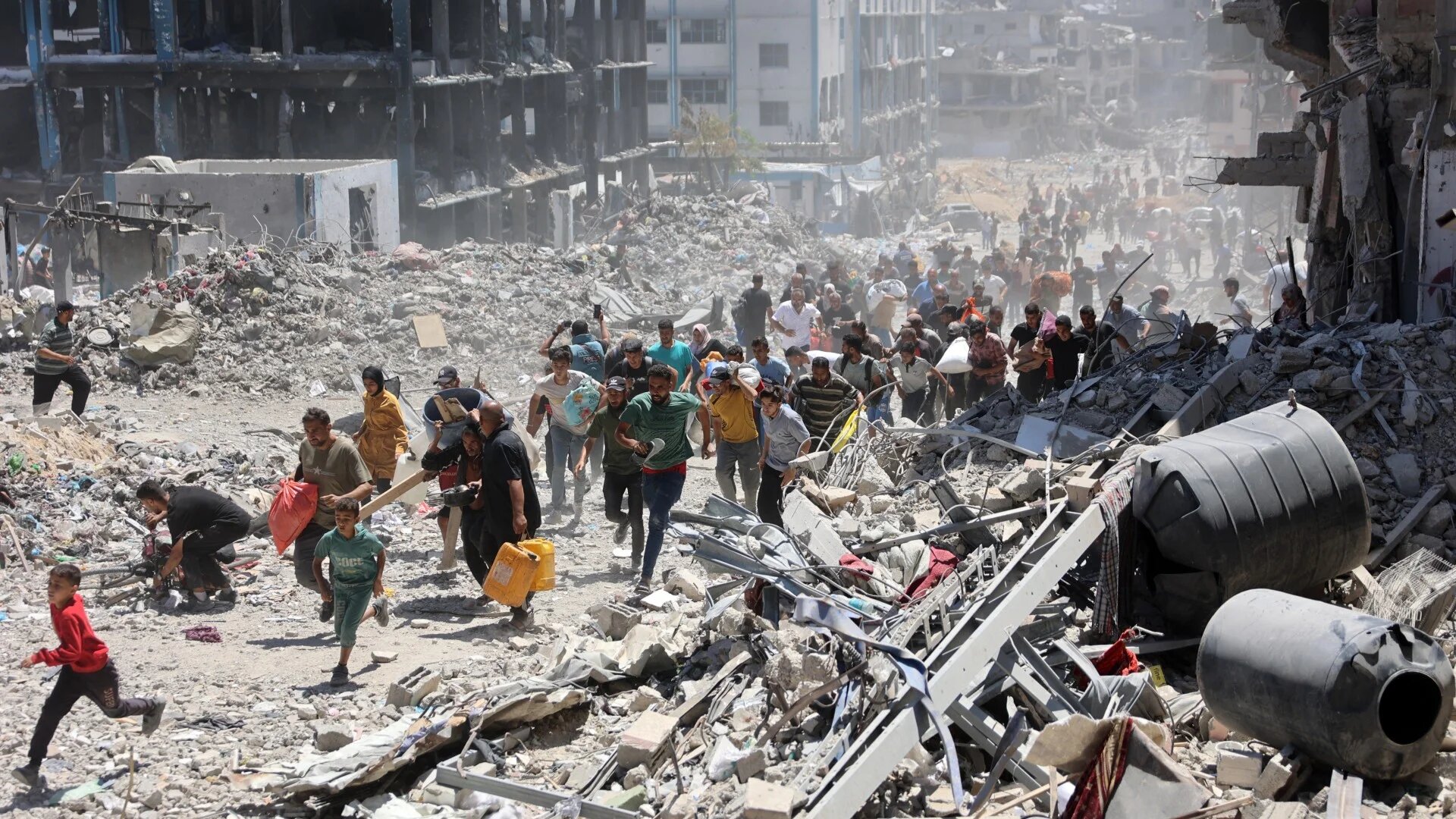 Palestinians who returned briefly to the Jabalia refugee camp in the northern Gaza Strip to check on their homes, run for cover after a school was hit by an Israeli strike on 30 May 2024 (AFP)