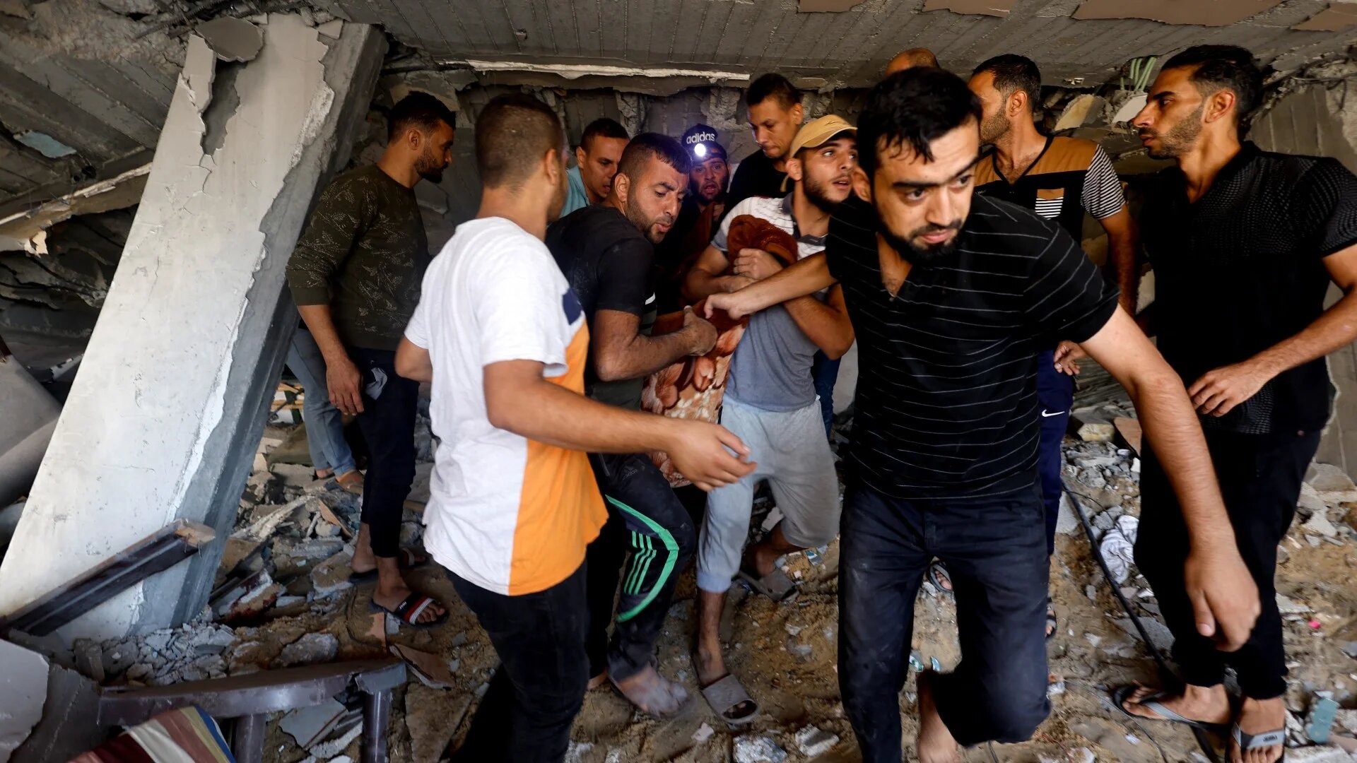 Palestinians carry a casualty at the site of Israeli strikes on a residential building on 7 November 2023 (Reuters)