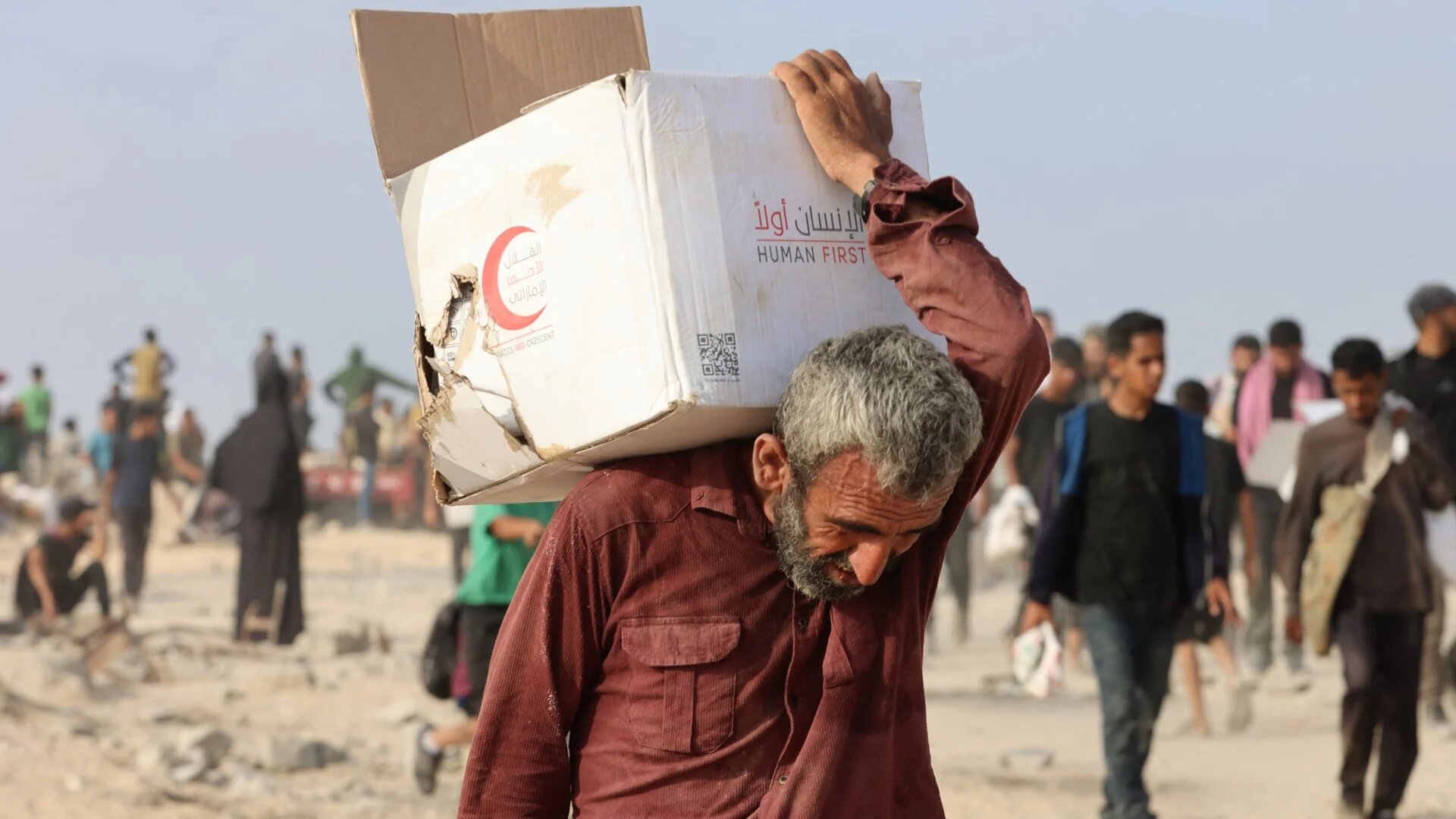 A man carries a box of aid along al-Rashid Street in western Jabalia on 22 June 2025 (AFP/Omar al-Qattaa)