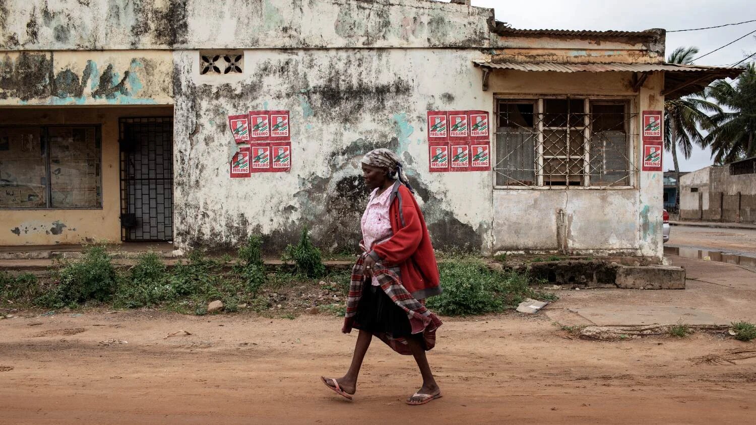 A woman walks by a wall plastered with Mozambican ruling party Mozambique Liberation Front campaign posters on 11 October 2019 in the Gaza Province, Mozambique.