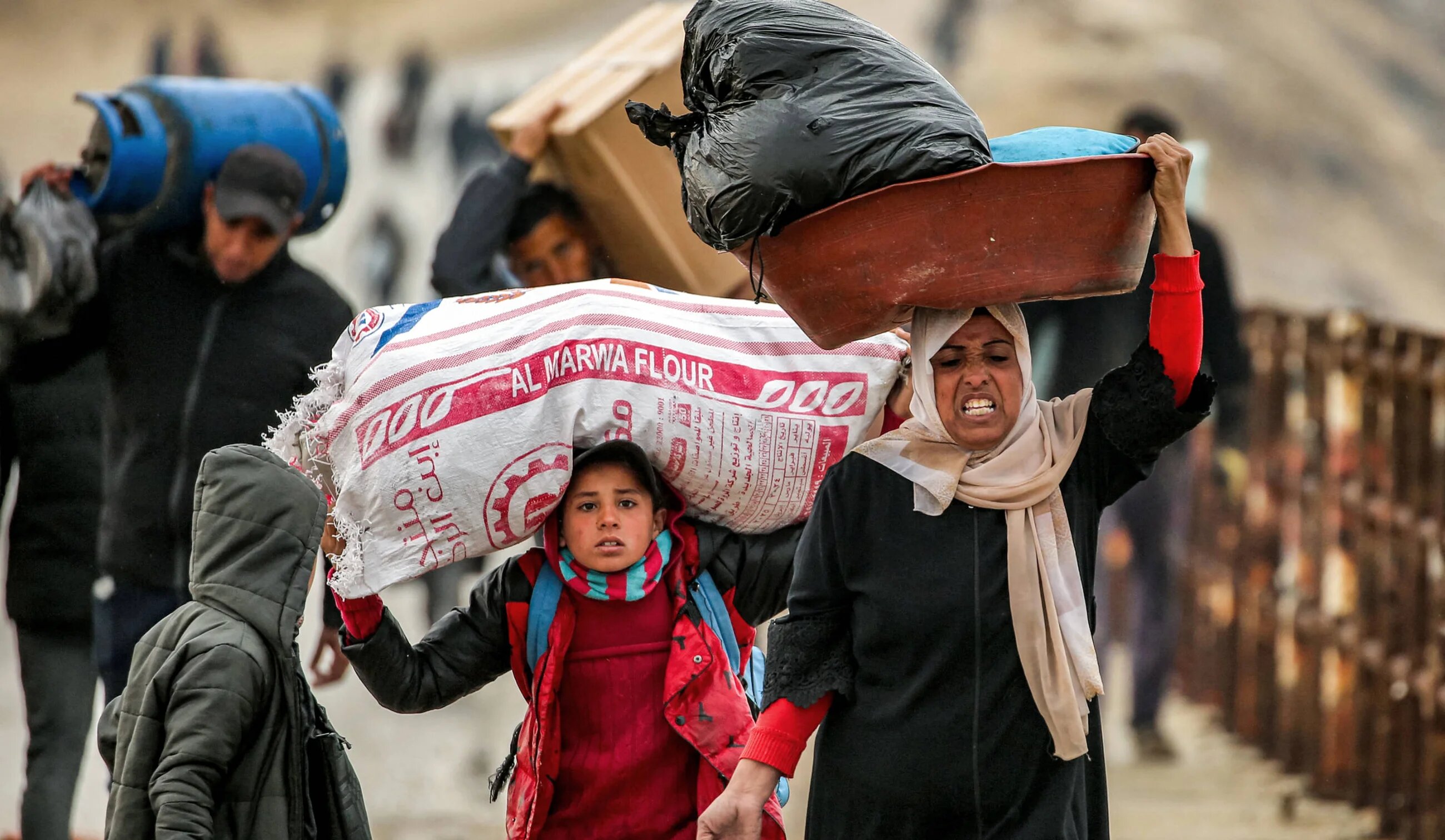 People walk with belongings along al-Rashid street between Gaza City and Nuseirat in the central Gaza Strip on 10 February 2025 as displaced people return home (AFP)