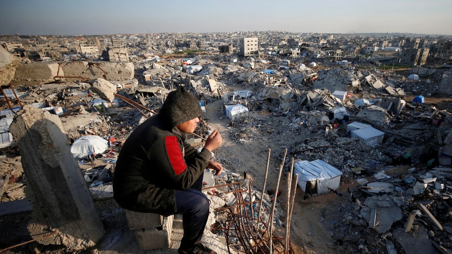 A Palestinian looks on as the rubble of destroyed buildings at Jabalia refugee camp, northern Gaza Strip, 26 February 2025 (Reuters/Mahmoud Issa)