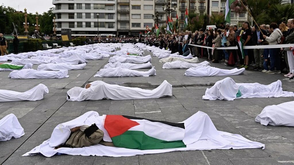 Demonstrators lie on the ground covered with white sheets as part of a protest against Israel’s war on Gaza in the Spanish Basque city of San Sebastian on 1 June 2025 (Ander Gillenea/AFP)