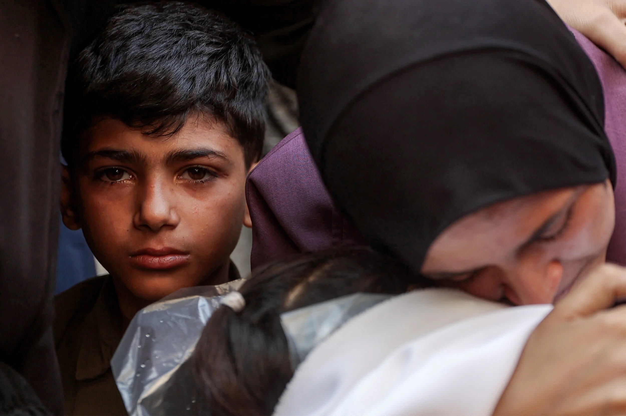 A boy looks on as a woman mourns over the body of a victim killed during overnight Israeli bombardment as she sits at al-Shifa hospital in Gaza City on 4 June 2025 (Omar al-Qattaa/AFP)