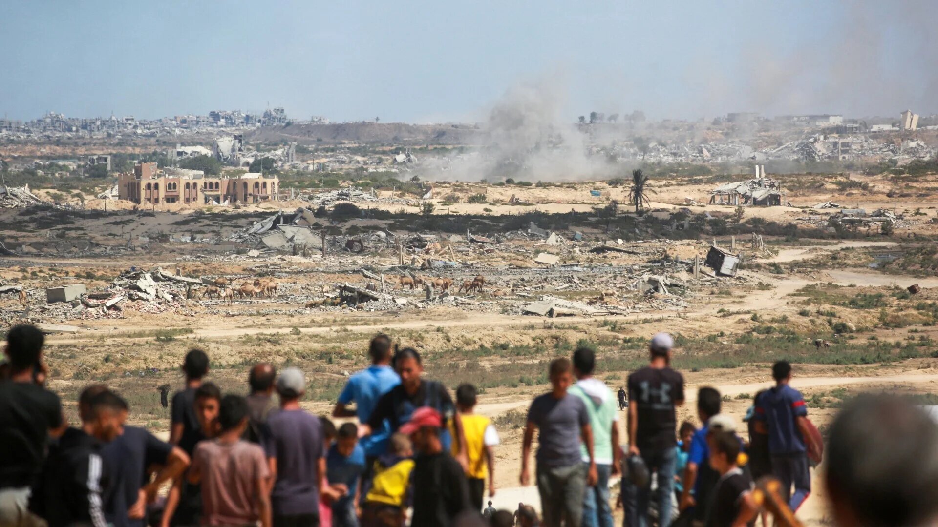 Palestinians watch smoke billowing during Israeli strikes upon arrival on a coastal path northwest of Nuseirat refugee camp on 1 October 2025 (AFP/Bashar Taleb)