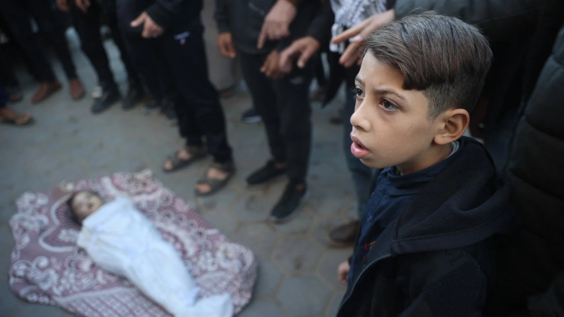 Palestinians pray over the body of a child, killed in an Israeli strike, at al-Aqsa Martyrs Hospital in Deir al-Balah in the central Gaza Strip on 15 December 2024 (Eyad Baba/AFP)