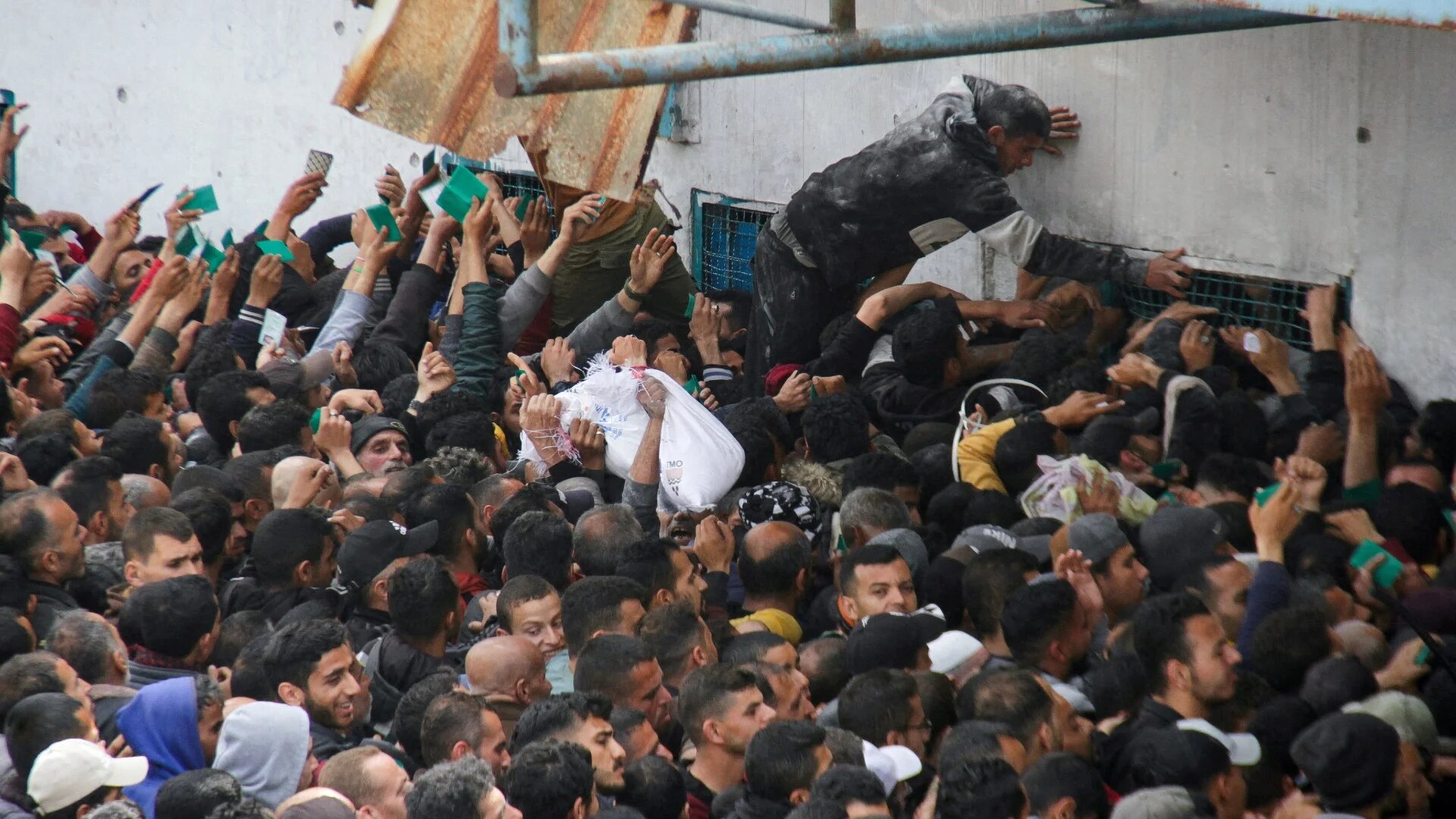 Palestinians gather to receive aid outside an Unrwa warehouse as Gaza residents face crisis levels of hunger, amid the ongoing Israeli offensive, 18 March 2024 (Reuters)