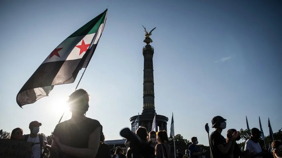 A protester in Berlin holds a Syrian flag on 20 September 2020 (Stefanie Loos/AFP)