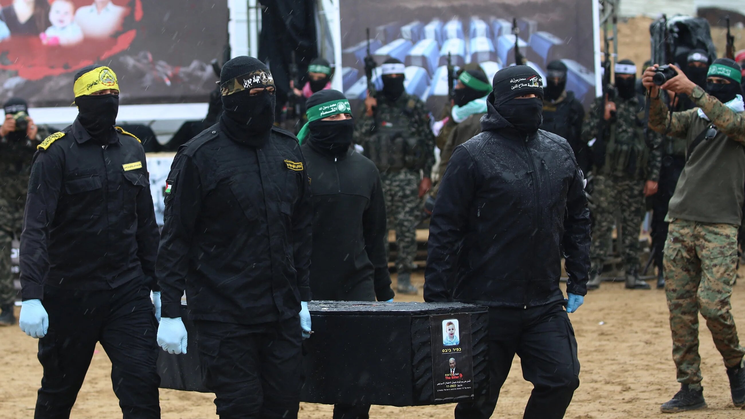 Hamas members carry one of the coffins during the handover of the bodies of four Israeli hostages in Khan Younis, southern Gaza, on 20 February 2025 (AFP/Eyad Baba)
