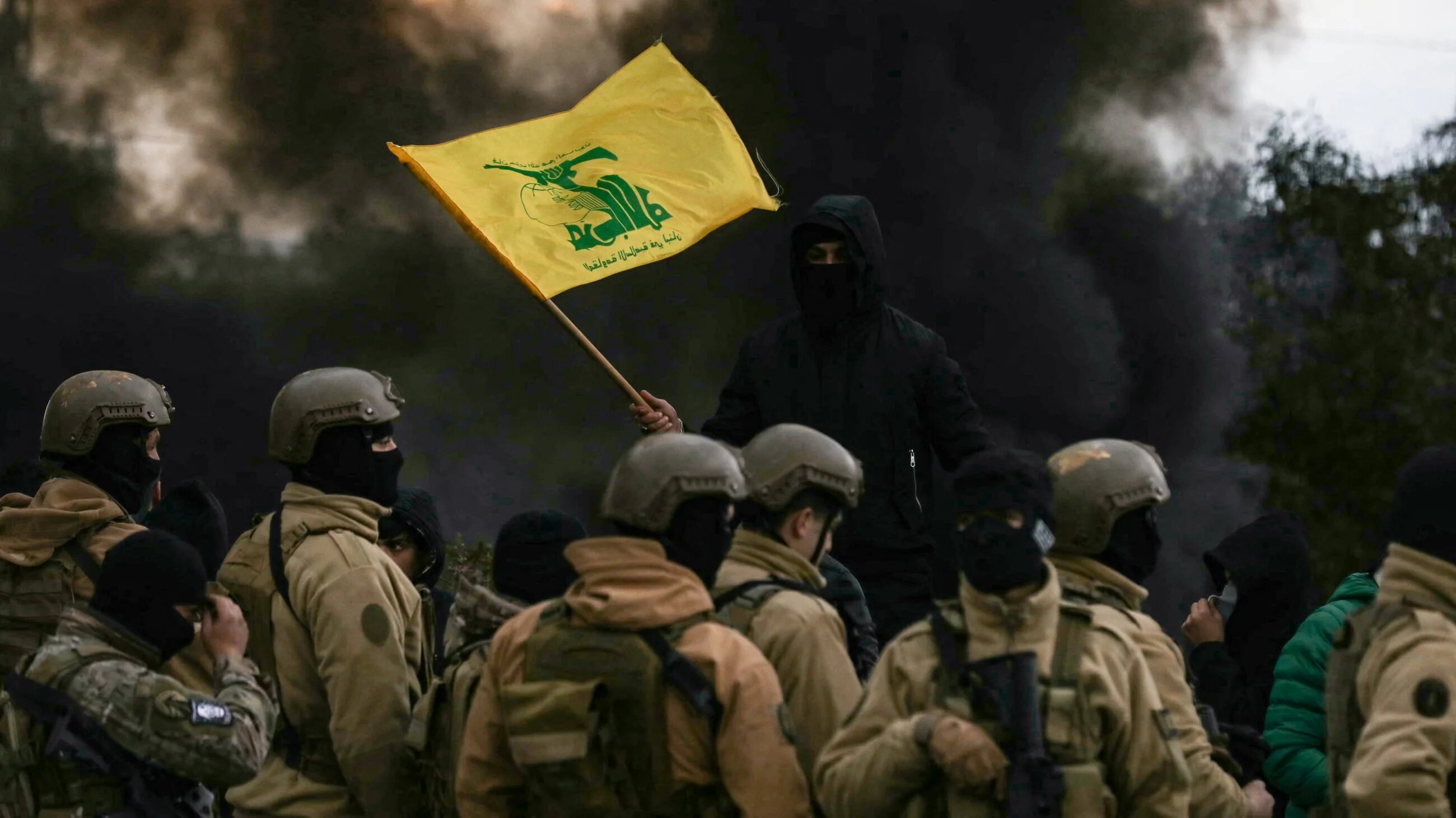 A Hezbollah supporter waves the group's flag in front of Lebanese army troops, 7 February 2025 (AFP)