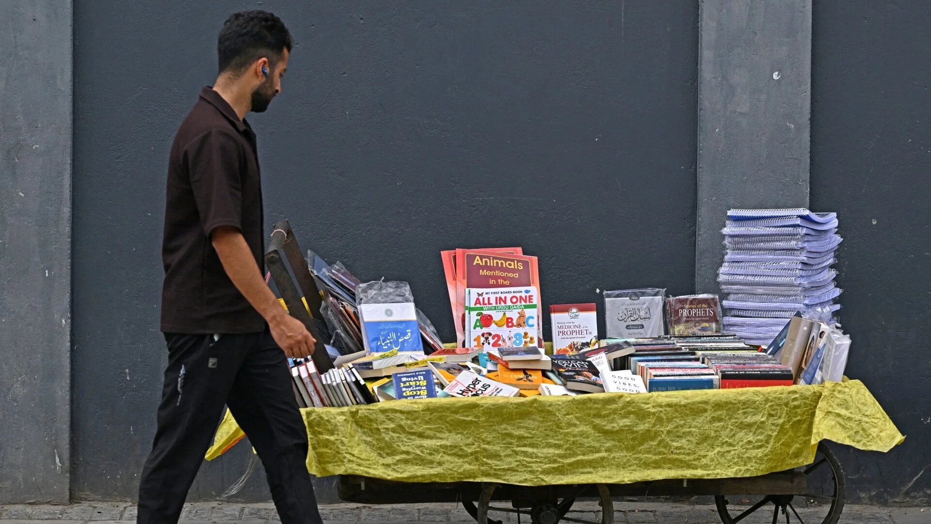 A pedestrian walks past a book cart along a roadside in Srinagar, in Indian-controlled Kashmir, on 7 August 2025 (Tauseef Mustafa/AFP)