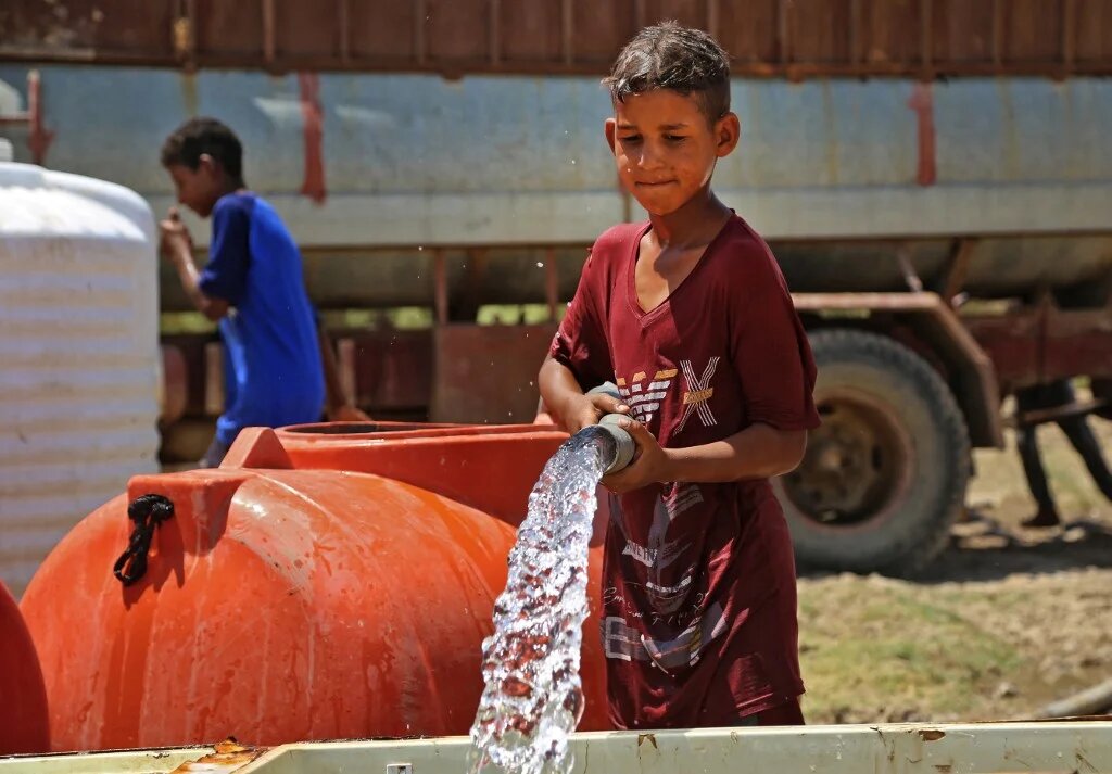 Un garçon puise de l’eau dans une citerne dans le village d’al-Aghawat, dans la province centrale de Diwaniya, en Irak, le 18 juillet 2022 (AFP/Haïdar Indhar)
