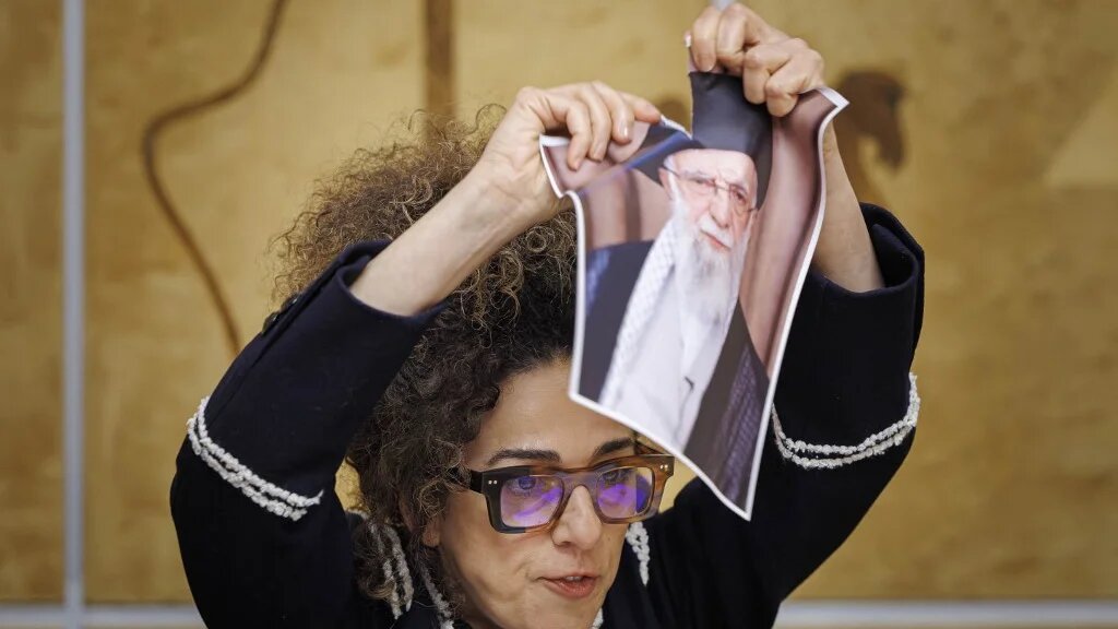 Iranian American activist Masih Alinejad tears up a picture of Iranian Supreme Leader Ali Khamenei, at the UN offices in Geneva on 17 February 2026 (Valentin Flauraud/AFP)