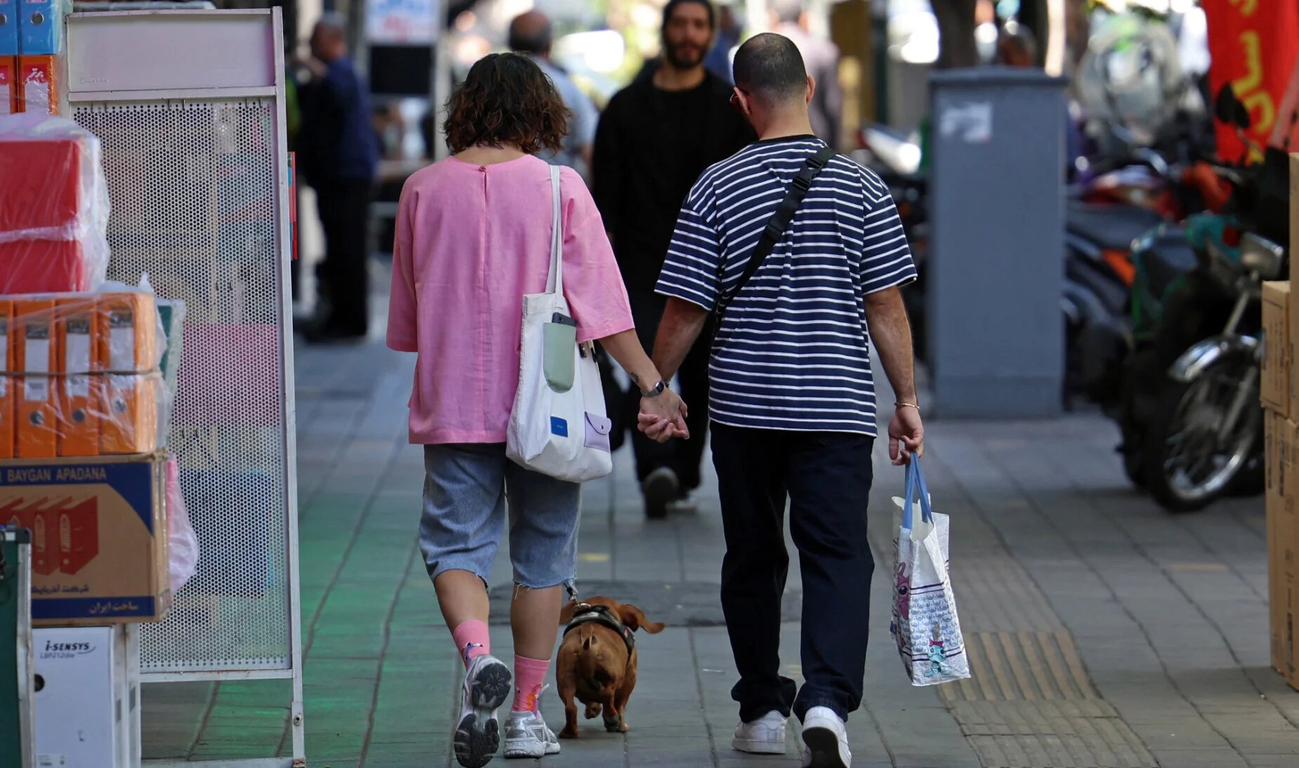 An Iranian couple walks along a busy street in Tehran on 25 April 2026 (AFP)