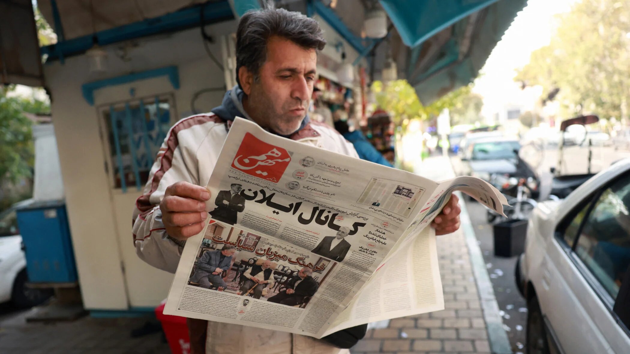 An Iranian man reads a copy of the Ham-Mihan daily newspaper at a bookstall in Tehran on 16 November 2024 (AFP)