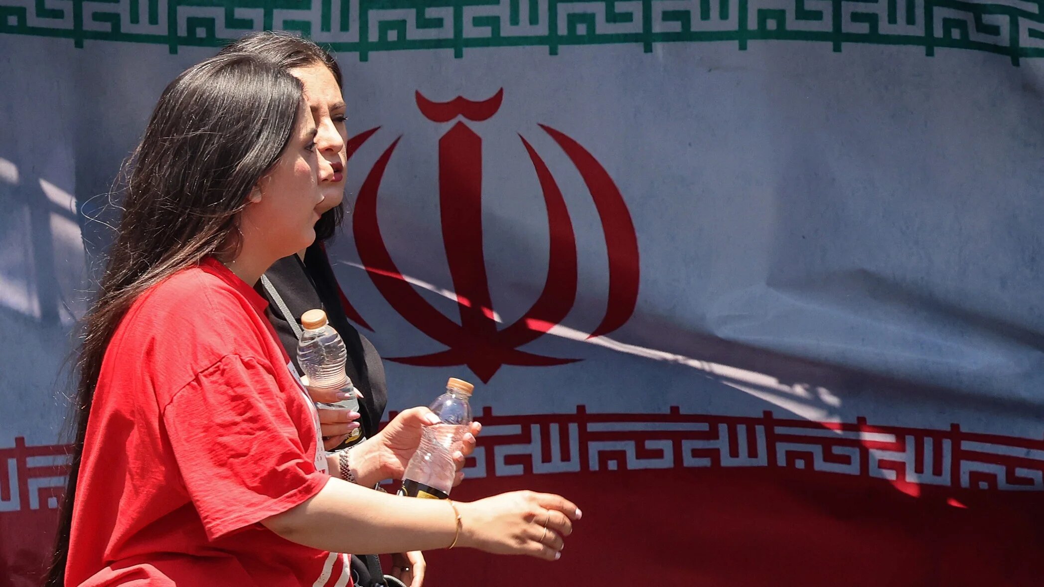 Iranian women walk past Iran's national flag at Vanak Square in Tehran on 10 June 2026 (Atta Kenare/AFP)