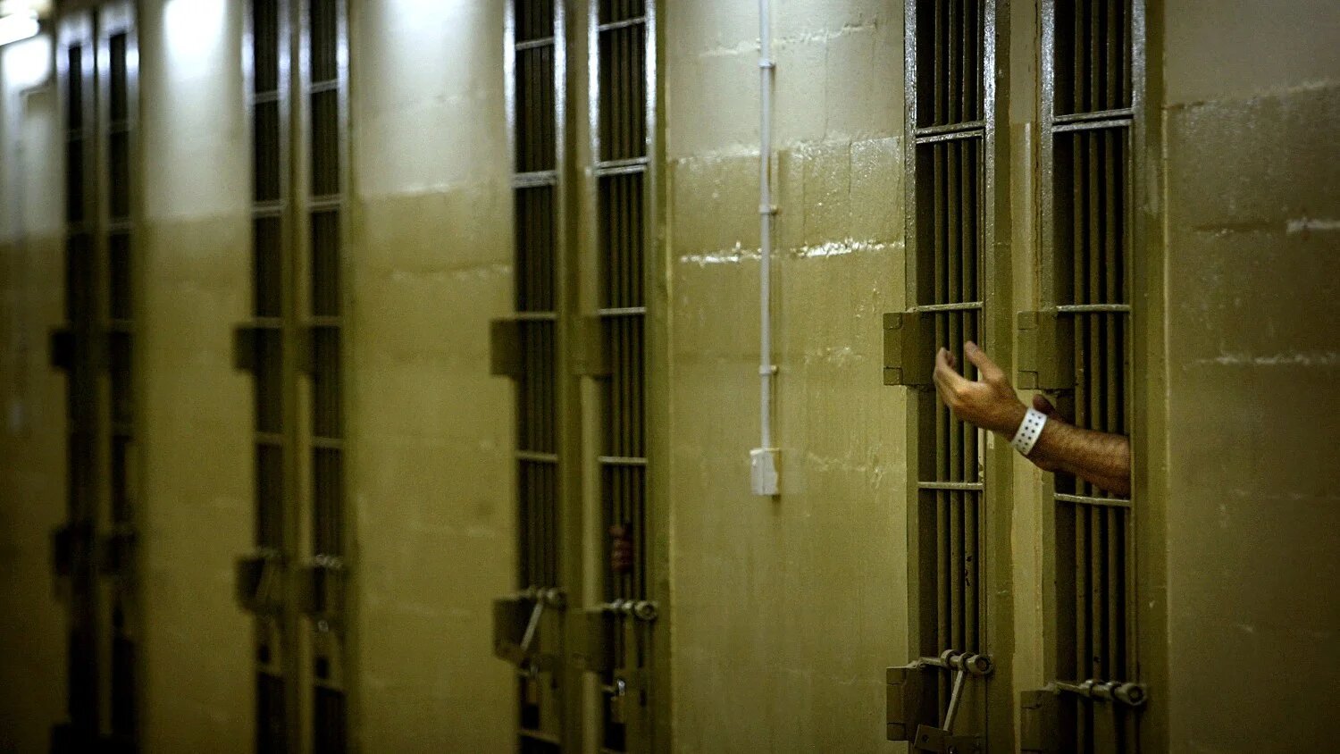 An Iraqi detainee gestures toward US soldiers through bars of his cell at Abu Ghraib prison outside Baghdad, Iraq on 17 May 2004.