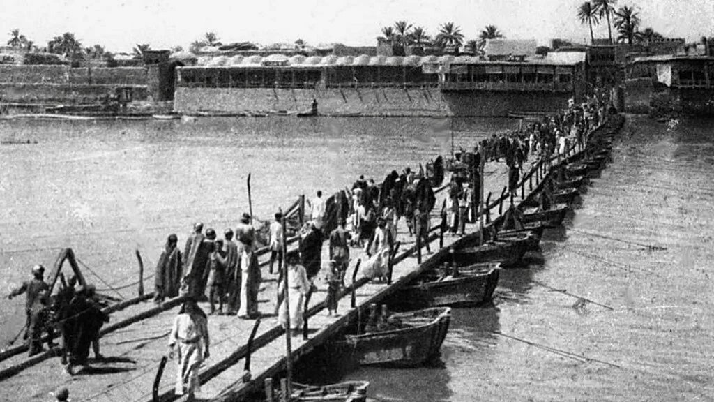 Iraqis walk across a bridge in Baghdad in 1932 (Karim Sahib/AFP)