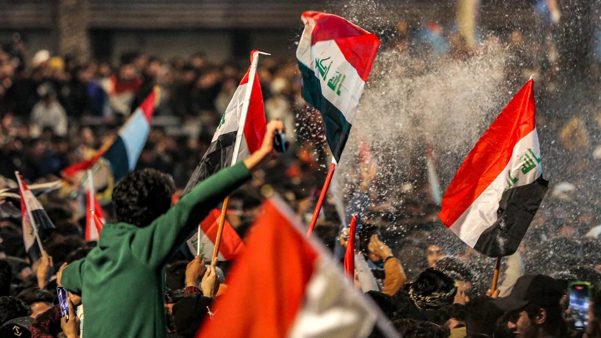 Fans spray foam as they celebrate in Baghdad on 19 January 2023 after Iraq defeated Oman to win the 25th Arabian Gulf Cup final match (AFP)