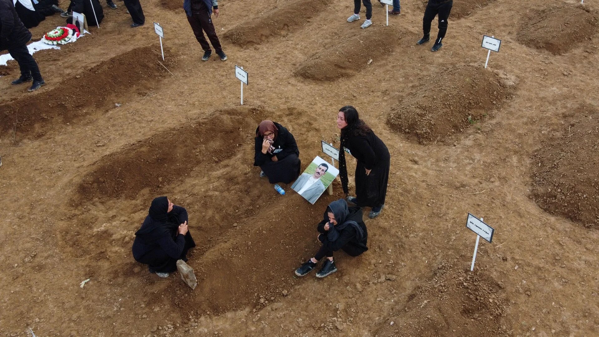 An aerial picture shows mourners gathering around graves during a mass funeral for Yazidi victims of the Islamic State (IS) group in the northern Iraqi village of Kojo in Sinjar district, on 6 February 2021 (AFP)