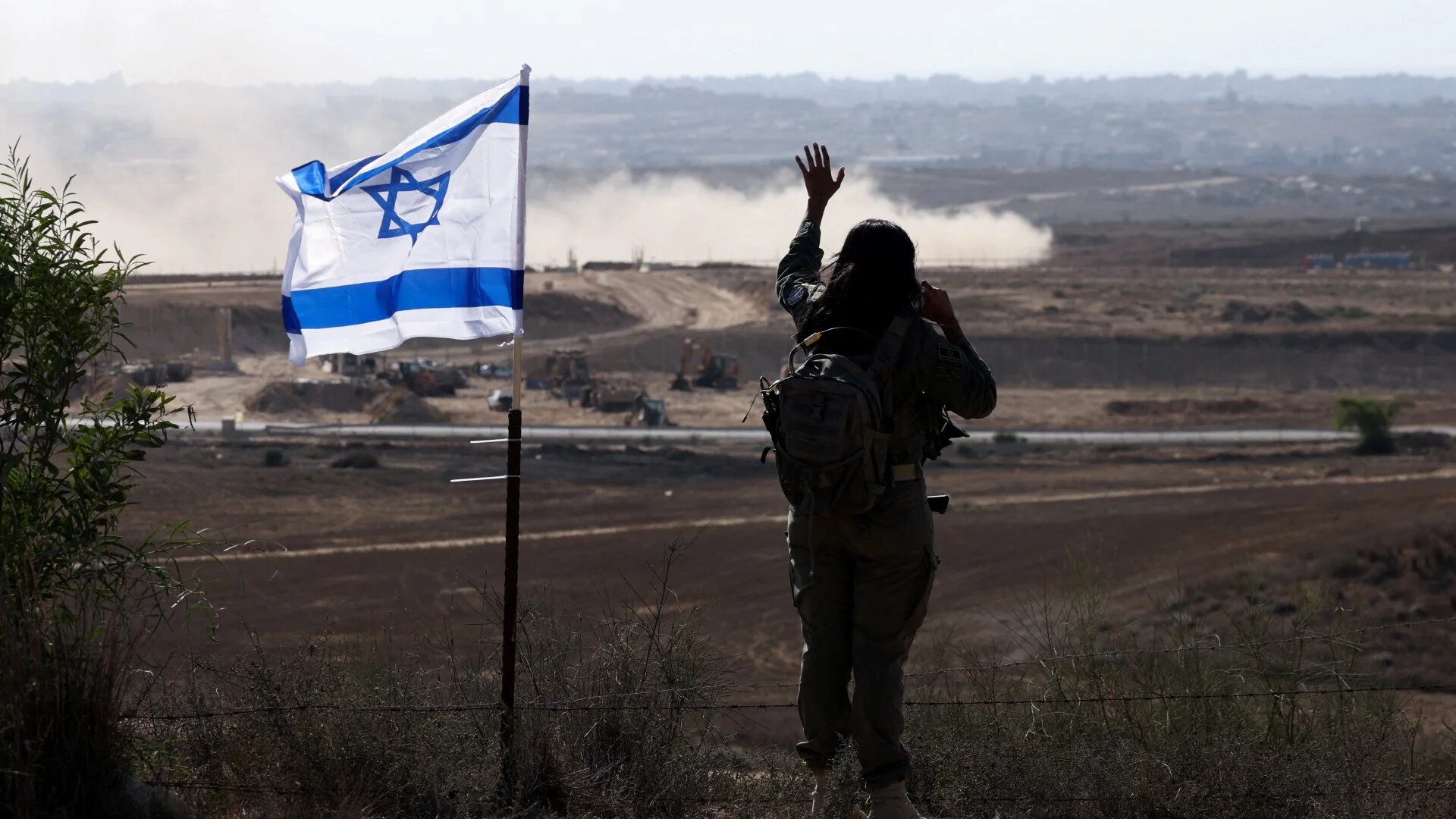 An Israeli soldier gestures in the direction of Gaza from the Israeli side of the boundary, 30 July, 2025 (Reuters/Ronen Zvulun)