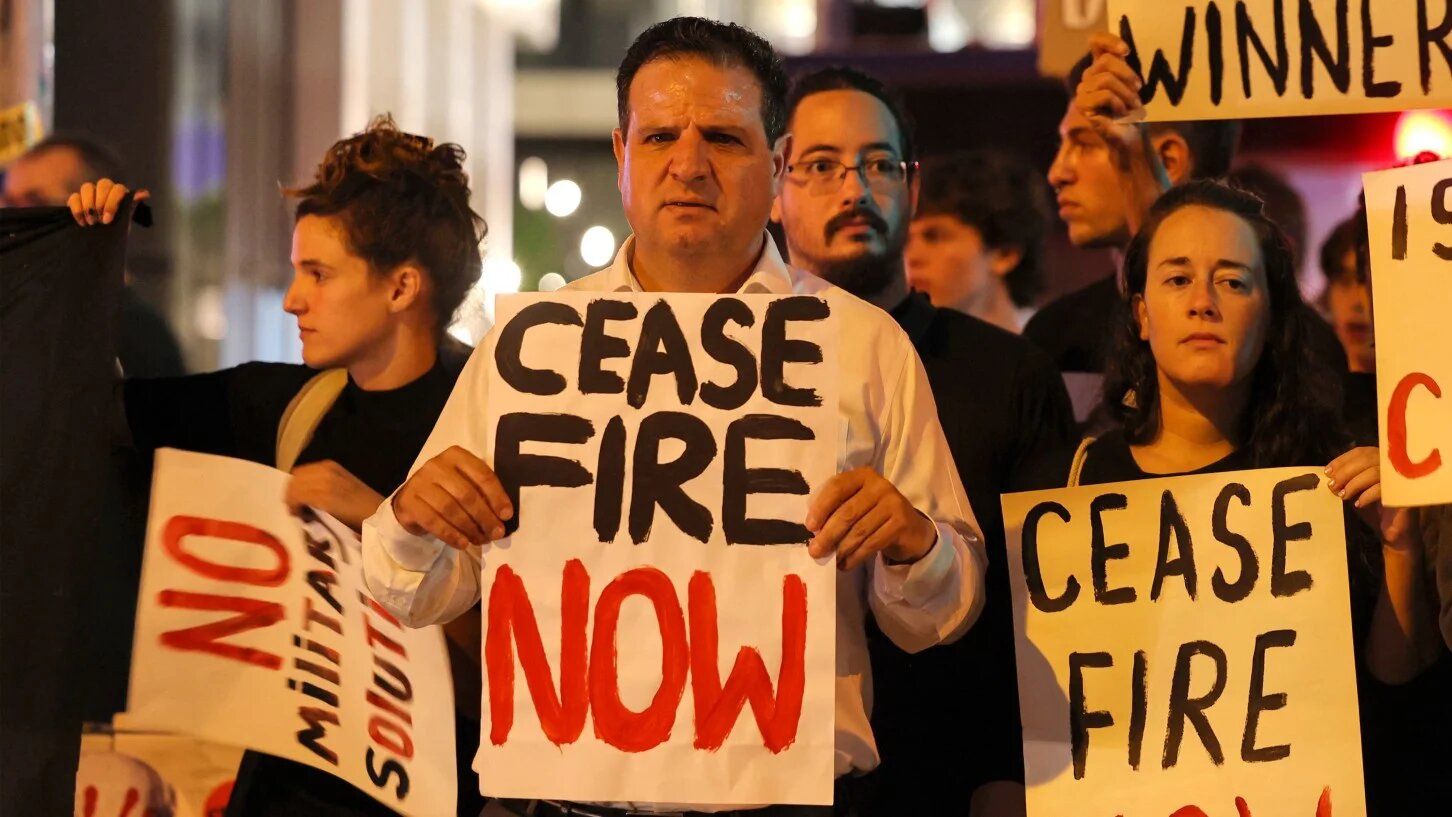 Knesset member Ayman Odeh (c) and Israeli left-wing activists hold placards during a demonstration against the war on Gaza in Tel Aviv on 4 November 2023 (Ahmad Gharabli/AFP)