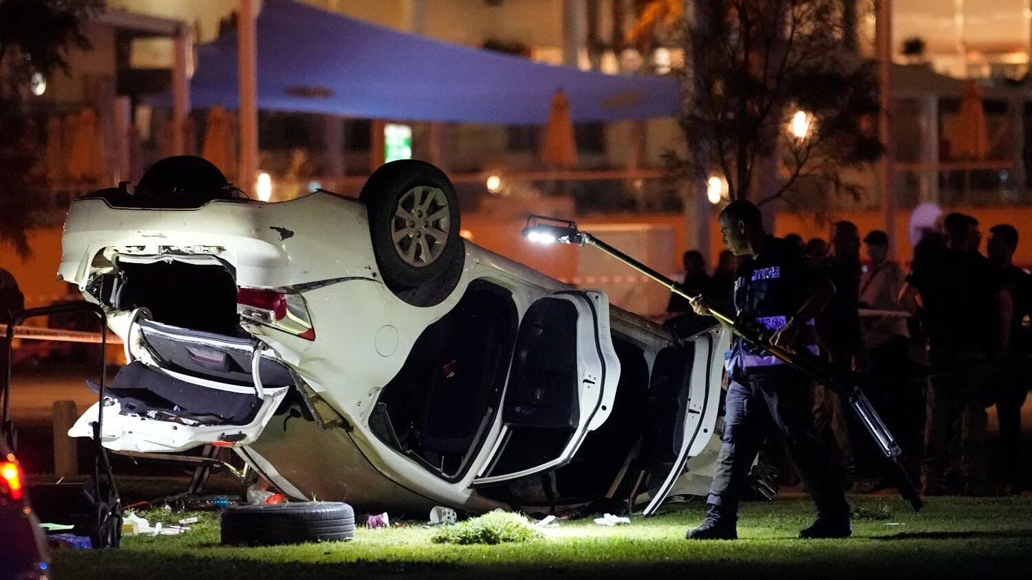 Israeli police and emergency service stand around a car involved in an attack in Tel Aviv, Israel, on 7 April 2023.