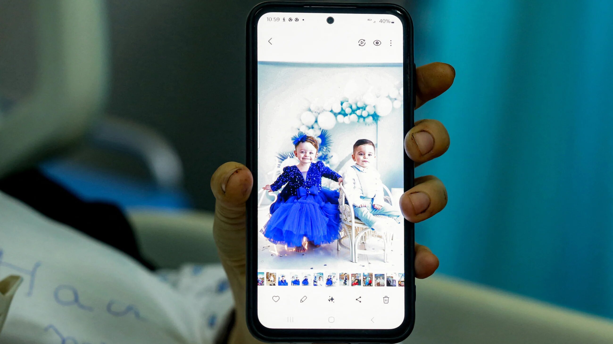 Amani Bazzi, a woman who was severely wounded by an Israeli drone strike the previous day in Bint Jbeil in southern Lebanon, shows pictures of her killed children on a phone as she rests at a hospital in Tebnine on 22 September 2025 (AFP)